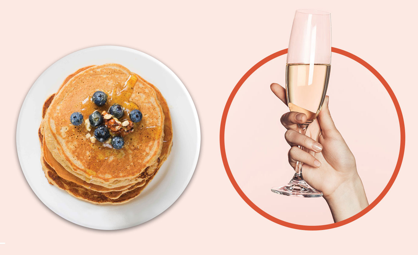 Image of a hand holding a glass of Champagne and a plate of pancakes for brunch