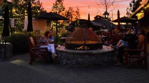Guests sitting around the outdoor fire pit as the sun sets in the distance.