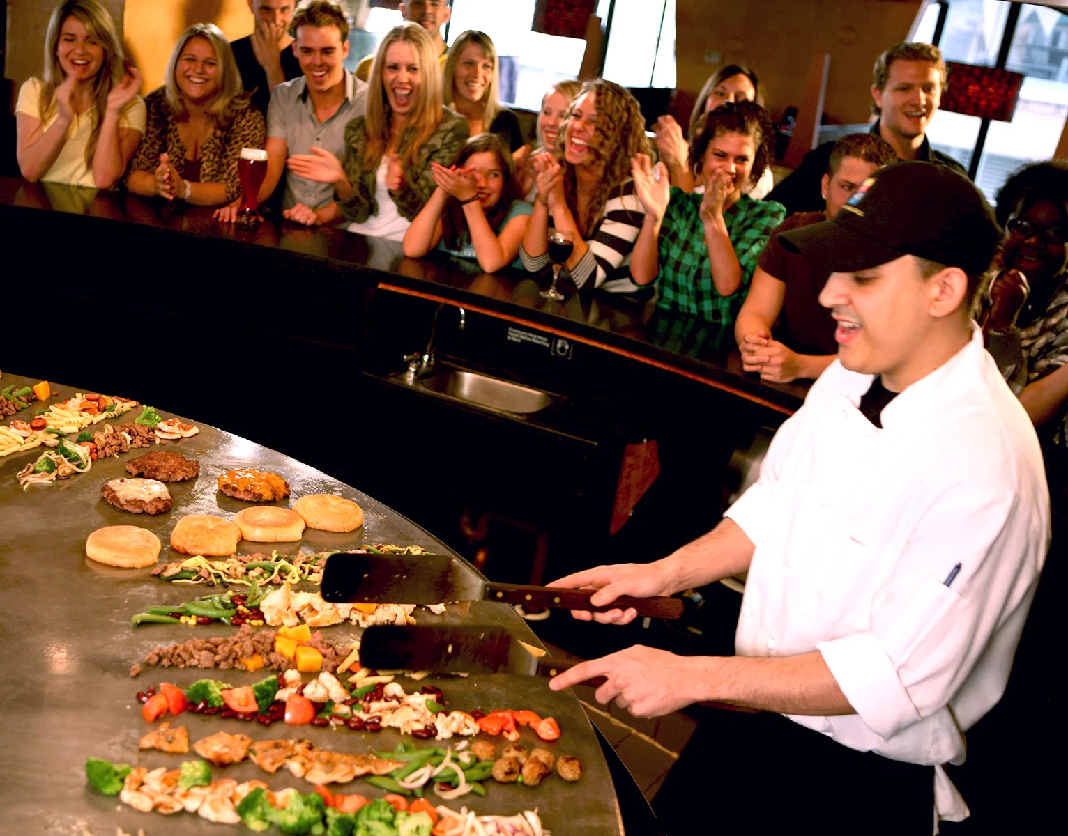 a Fire + Ice grill cook cooking food while an excited crowd looks on