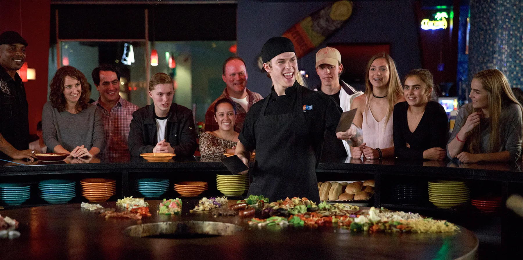 a Fire + Ice grill cook looking excited and cooking food while an excited crowd looks on