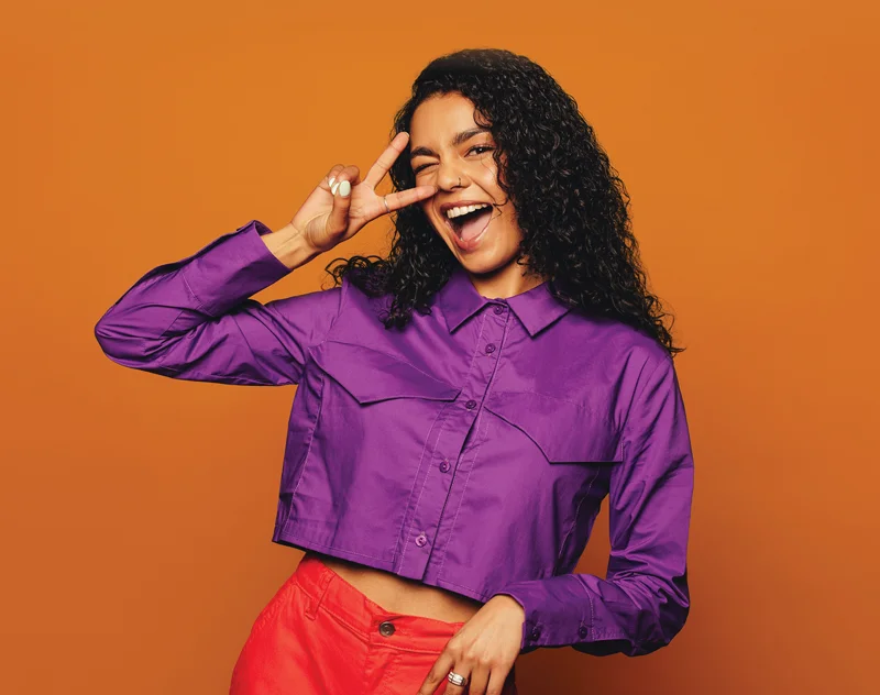 a young woman playfully putting two fingers up over her eye to indicate the number 2