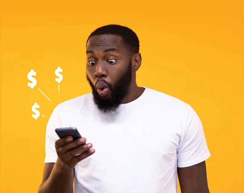 a young man looking excitedly at his phone with dollar signs surrounding the phone