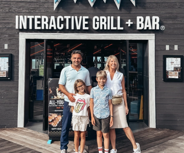 Mother and father with 2 young children pose in front of Fire + Ice restaurant on Pier 39 in San Francisco