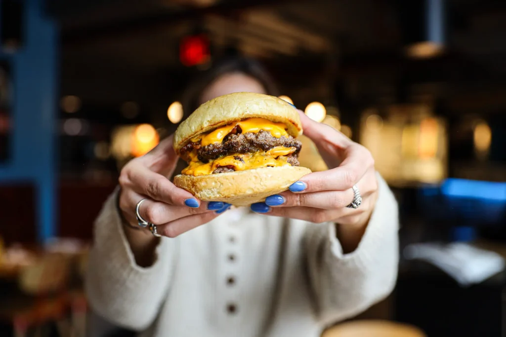 double smashburger held by two hands close to the camera