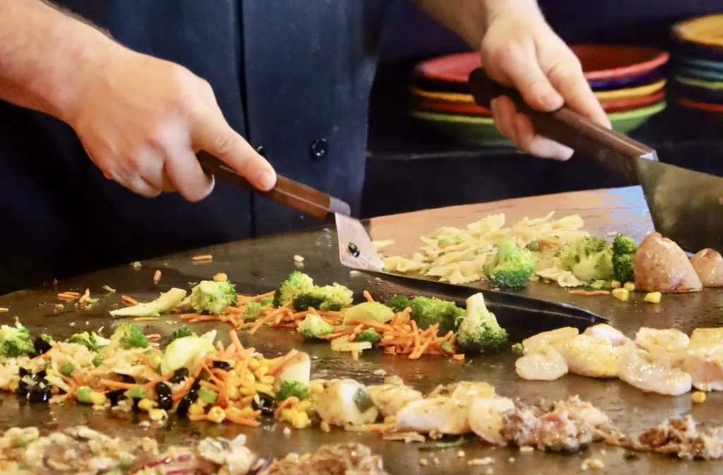 proteins & vegetables being cooked on the round top grill at Fire + Ice