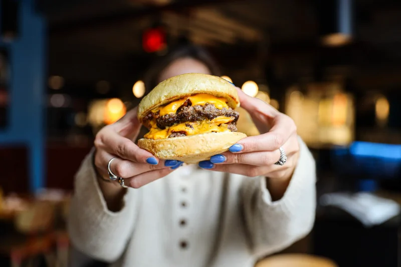 double smashburger held by two hands close to the camera